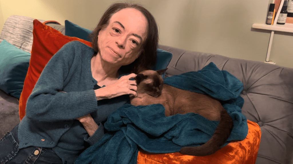 The actress Liz Carr sitting on the couch with her pet cat Ella