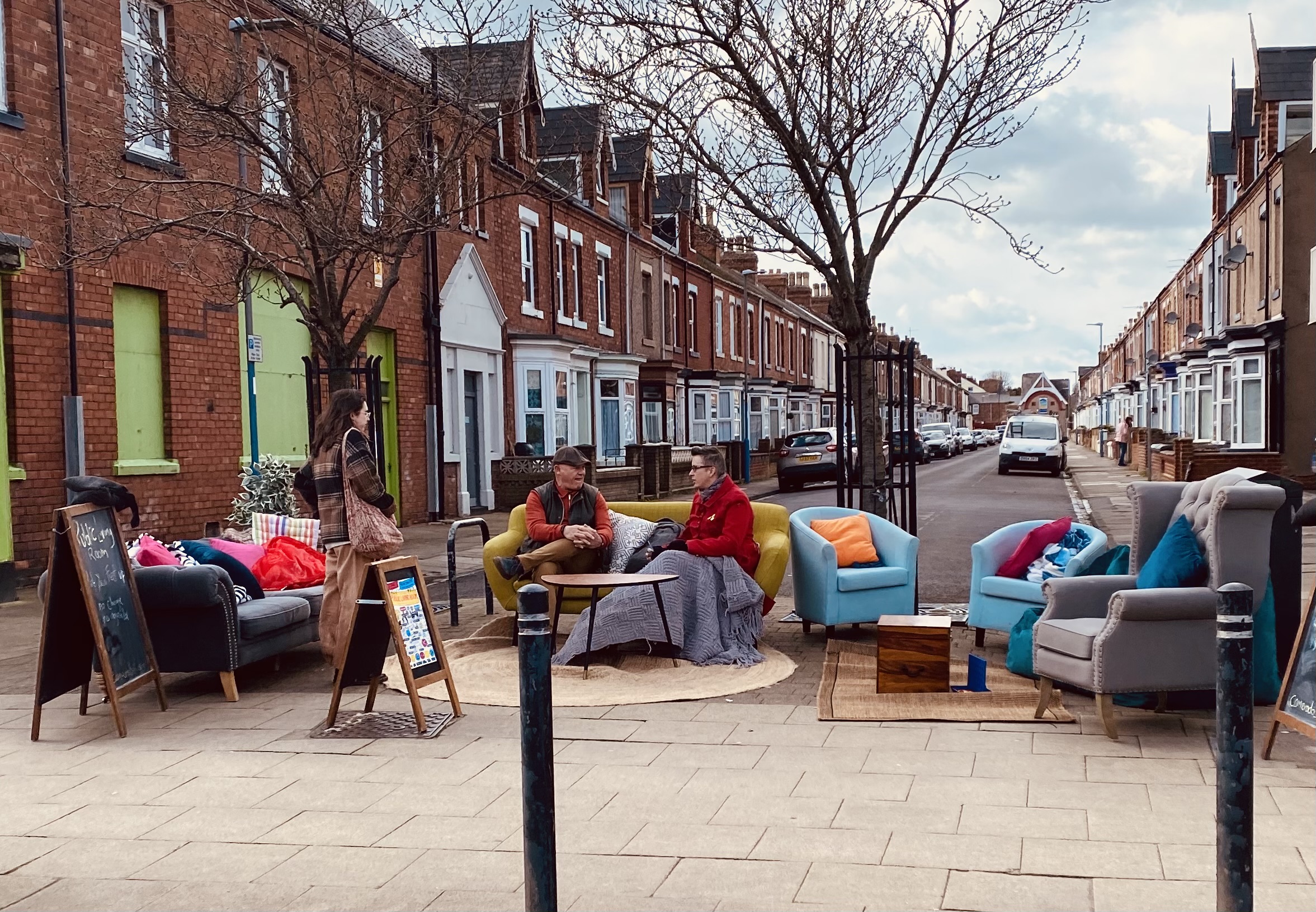 People sat on couches in an outdoor living room, having a chat in a suburban street