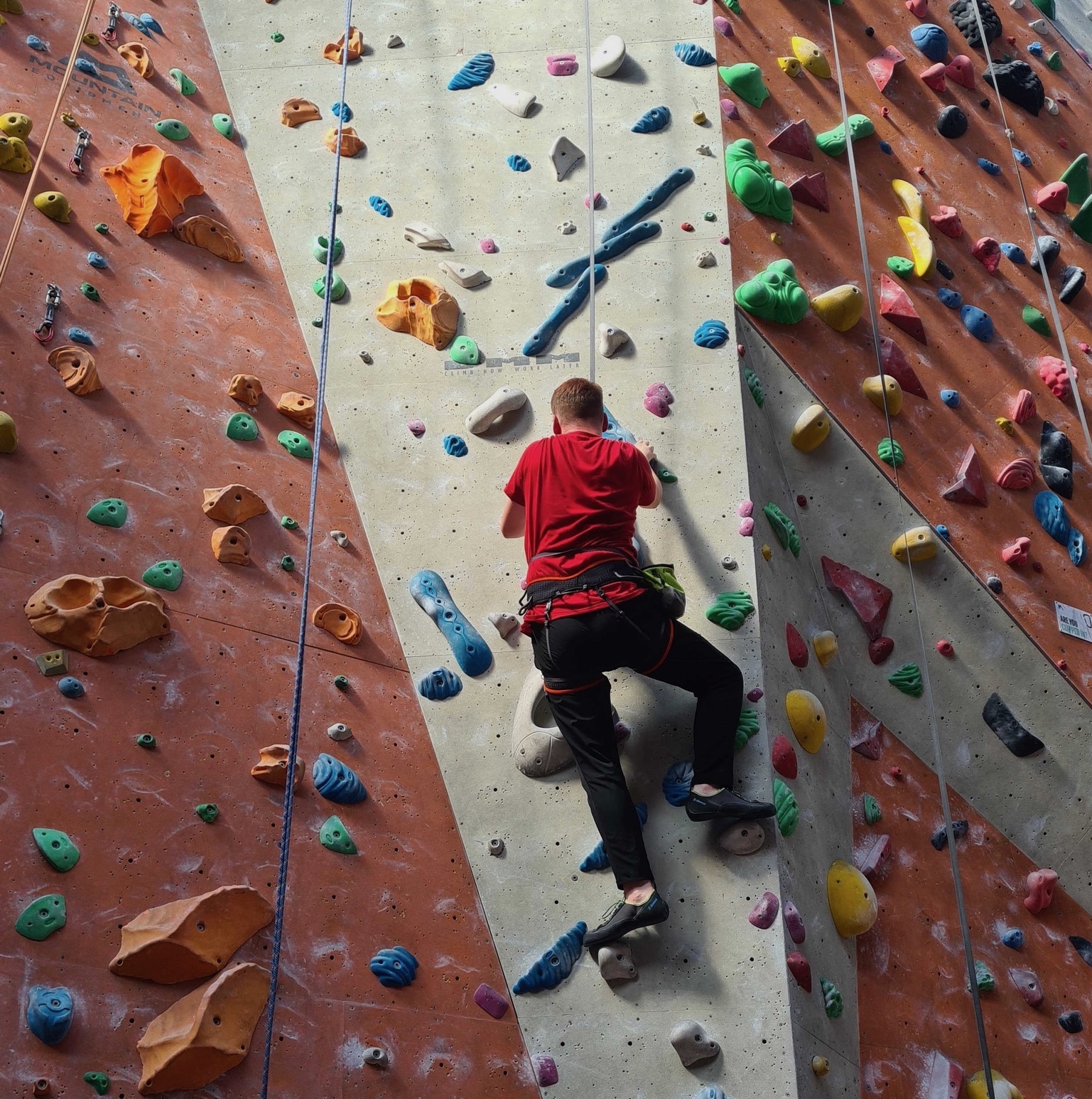 A young man climbing up a climbing wall