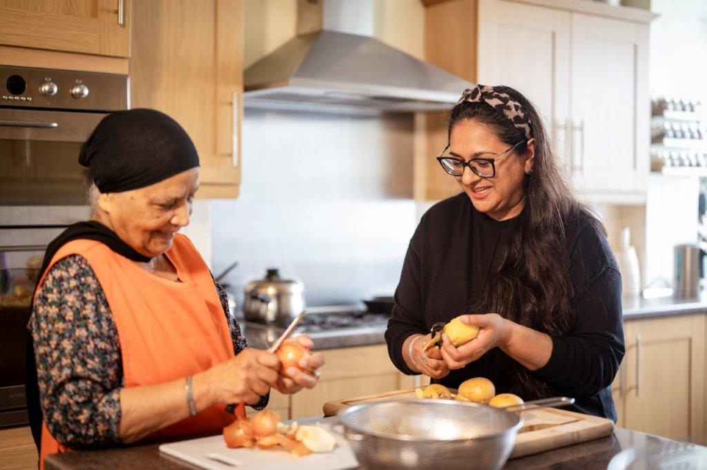 Image of two women, of different ages, preparing food together in a kitchen