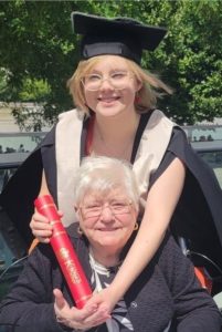 Penny on her graduation day with her gown and cap and certificate hugging her grandma, Pat, who is also Julie's mum